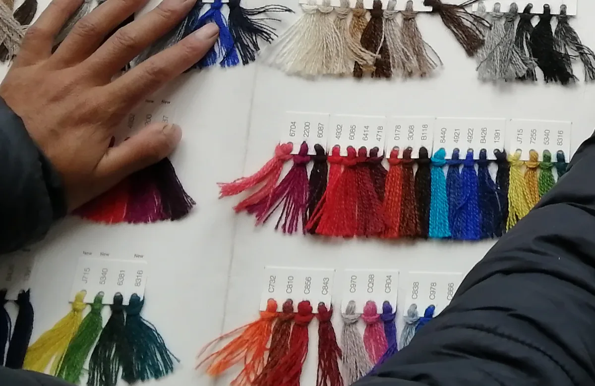 Hands over the yarn colour card, choosing the colour before knitting.