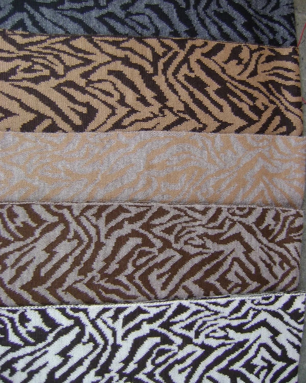 Chalinas de jacquard dobladas una sobre otra, en los tonos naturales de la fibra: crudo, beige y marrón.