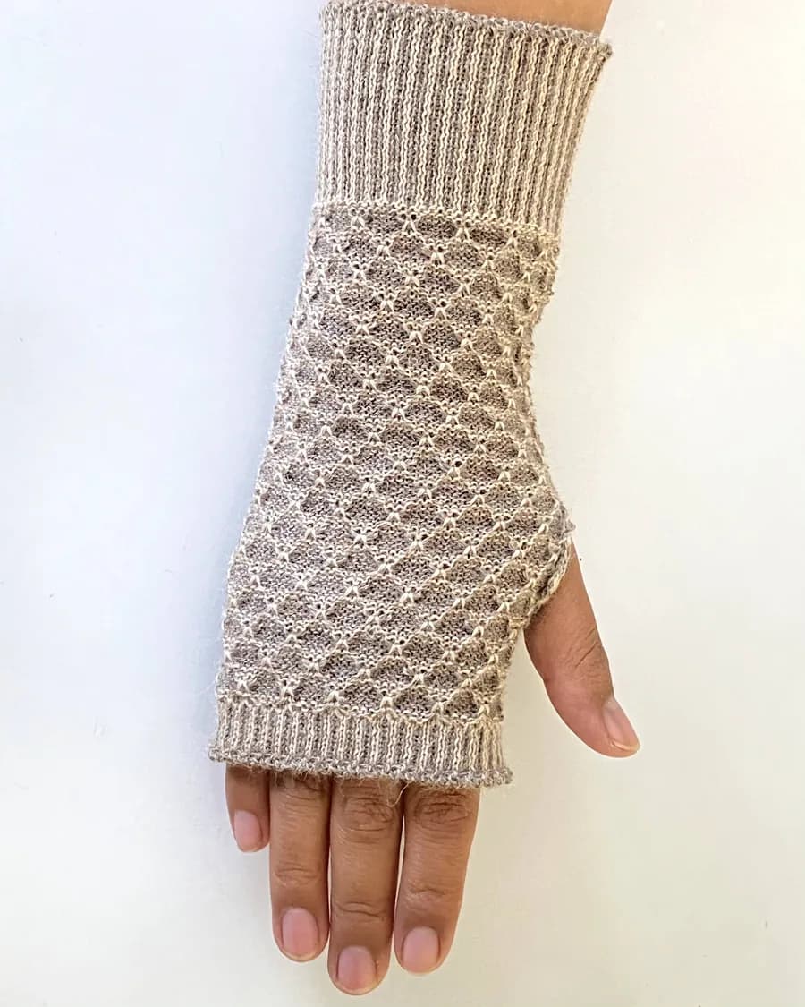 Mitón sin dedos en baby alpaca beige, de punto de panal, puesto en la mano.