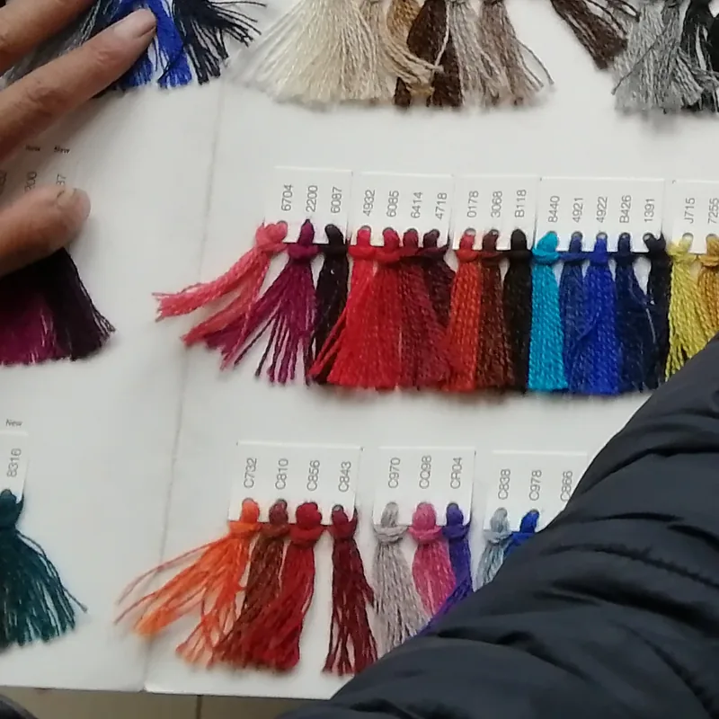 Manos sobre la cartilla de hilados, eligiendo el color antes de tejer.