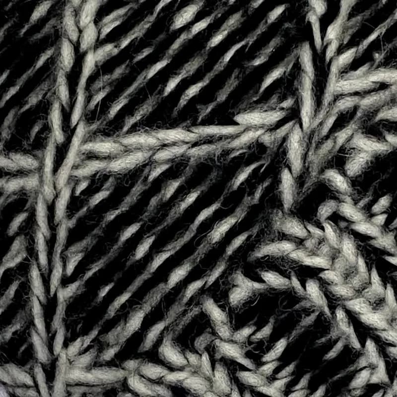 Detalle del punto: rombos en relieve, tejidos en hilo grueso jaspeado en negro y crudo.