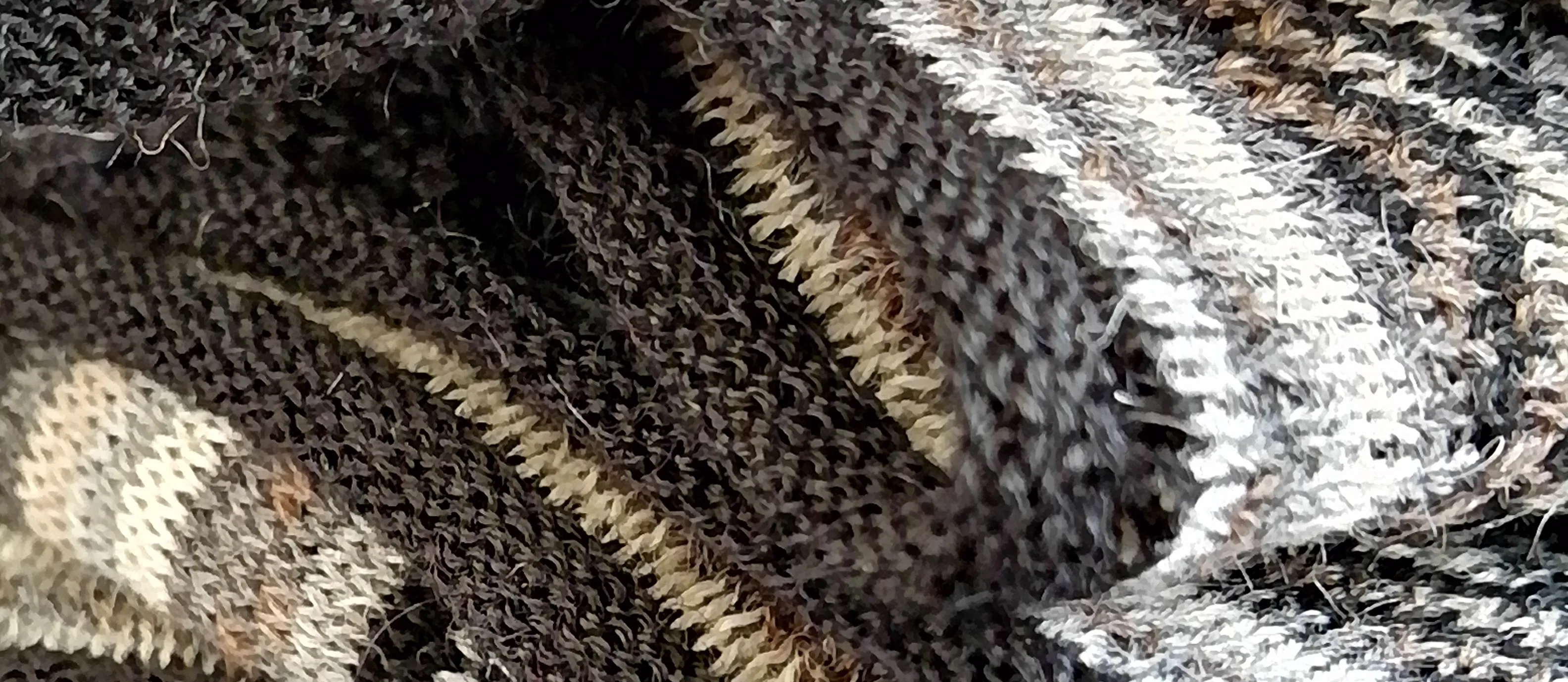 Chalinas de alpaca dobladas una sobre otra, en los tonos naturales de la fibra: crudo, beige, marrón y negro.